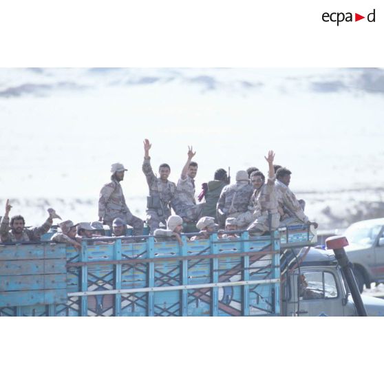 Des soldats saoudiens debout à l'arrière d'un camion civil saluent l'objectif.