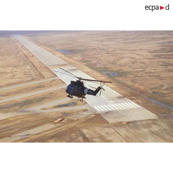 Vue aérienne d'un hélicoptère de transport Puma SA-330 de l'ALAT (aviation légère de l'armée de terre) survolant la piste d'envol de la base aérienne d'Al Salman, endommagée par les soins du 6e REG (régiment étranger du génie).