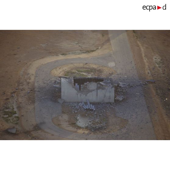 Vue aérienne d'une hangarette détruite sur la base aérienne d'Al Salman avec des impacts d'explosions.