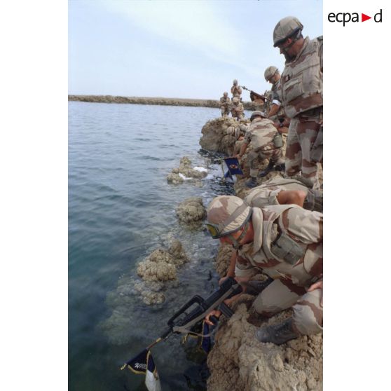 Lors de la cérémonie militaire franco-américaine sur les bords du fleuve Euphrate, des militaires français trempent dans l'eau les fanions de leurs unités.