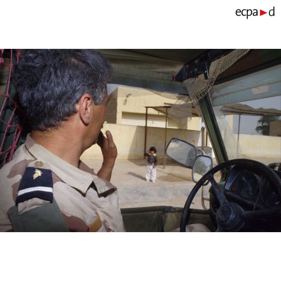 Un adjudant photographe salue un enfant d'Al Salman depuis l'intérieur du véhicule Peugeot P4 de l'ECPA (Etablissement cinématographique et photographique des Armées).