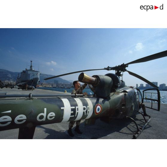 Au port de Toulon, un mécanicien du 3e RHC (régiment d'hélicoptères de combat) s'affaire sur la turbine d'un hélicoptère de combat Gazelle déchargé du TCD (transport de chalands de débarquement) Foudre amarré au quai.