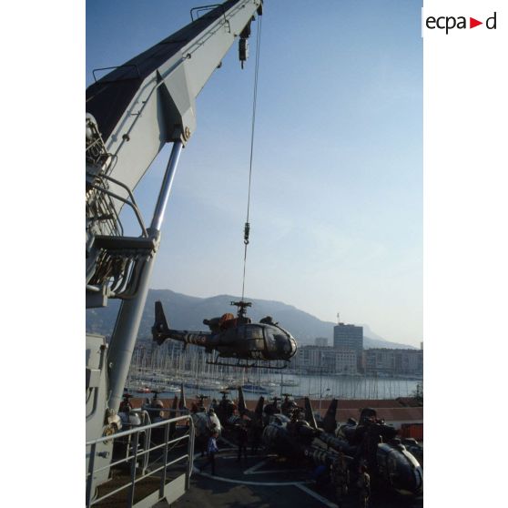 Un hélicoptère de combat Gazelle du 3e RHC (régiment d'hélicoptères de combat) est treuillé par une grue du TCD (transport de chalands de débarquement) Foudre vers le quai du port de Toulon.