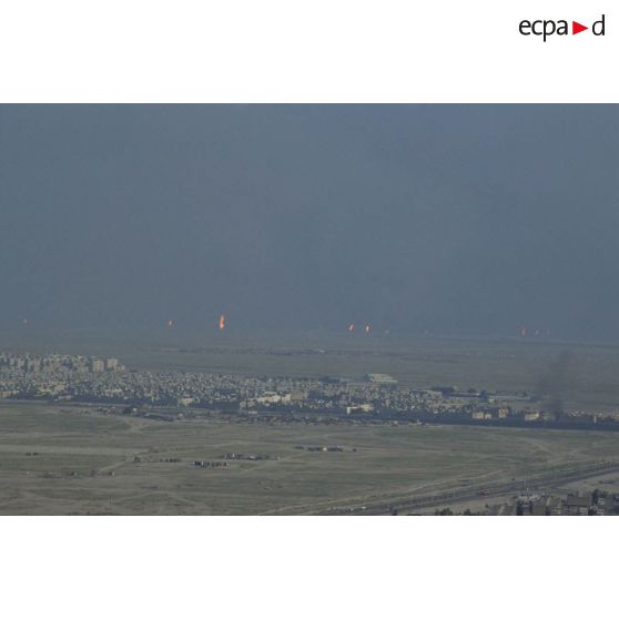 Vue aérienne de la ville de Koweit City. A l'arrière-plan, des puits de pétrole brûlent.