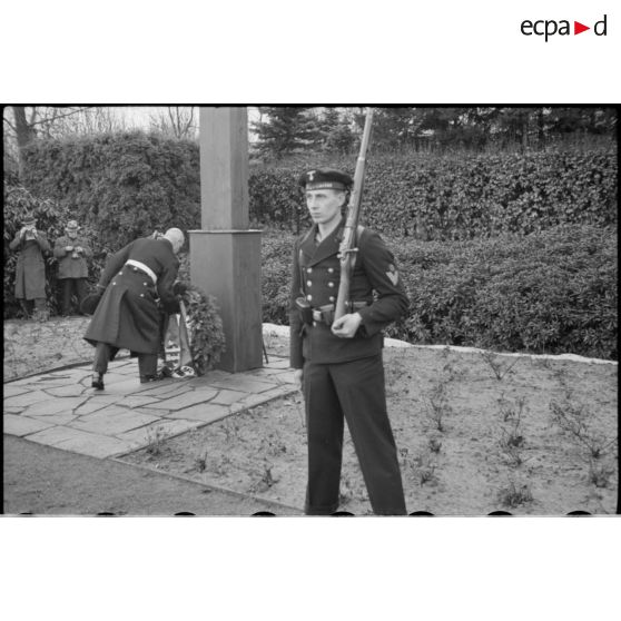L'amiral Hermann Densch dépose une couronne au pied d'un monument en forme de croix.