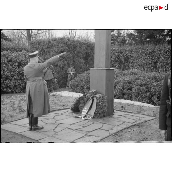Lors d'une cérémonie d'hommage, des cadres du NSDAP déposent des couronnes mortuaires au pied d'une croix.