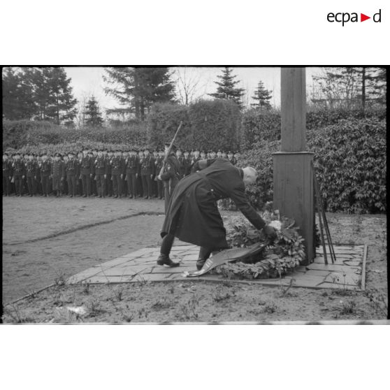 Lors d'une cérémonie d'hommage, des cadres du NSDAP déposent des couronnes mortuaires au pied d'une croix.
