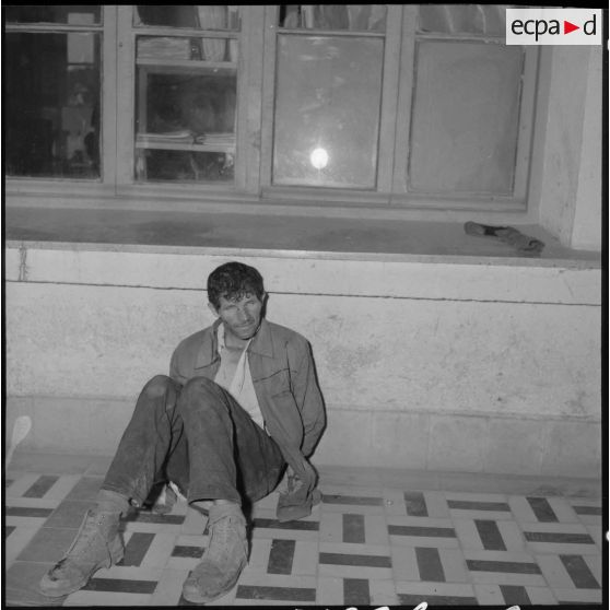 Un prisonnier assis dans un couloir.