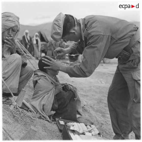 Douar Aïn Hamiane. Un soldat soigne un enfant survivant du massacre de Mechta Kasbah.