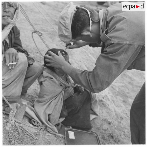 Douar Aïn Hamiane. Un soldat soigne un enfant survivant du massacre de Mechta Kasbah.