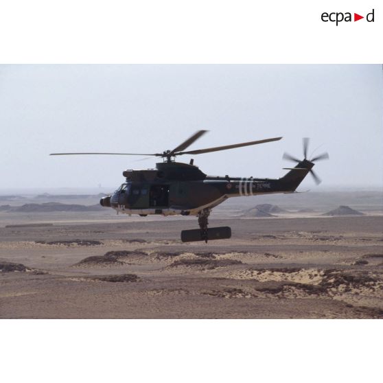 Un hélicoptère de transport Puma Orchidée (observatoire radar cohérent héliporté d'investigation des éléments ennemis) survole le désert saoudien.