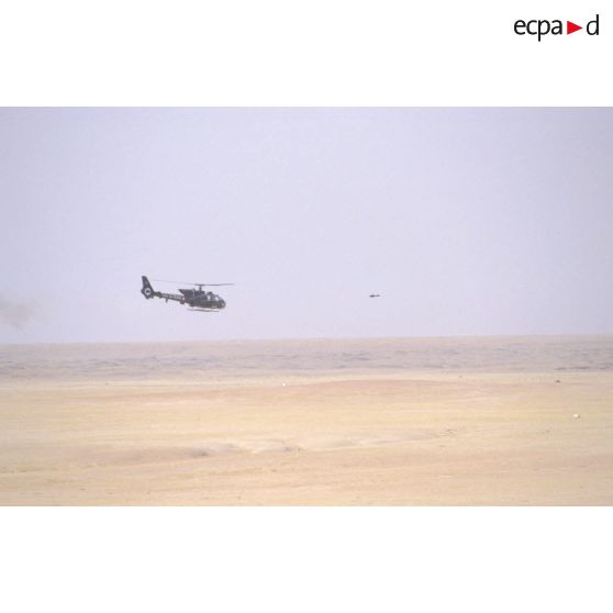 Hélicoptère de combat Gazelle SA-342 en vol d'entraînement au tir de missiles HOT. Le missile est en vol devant l'hélicoptère.