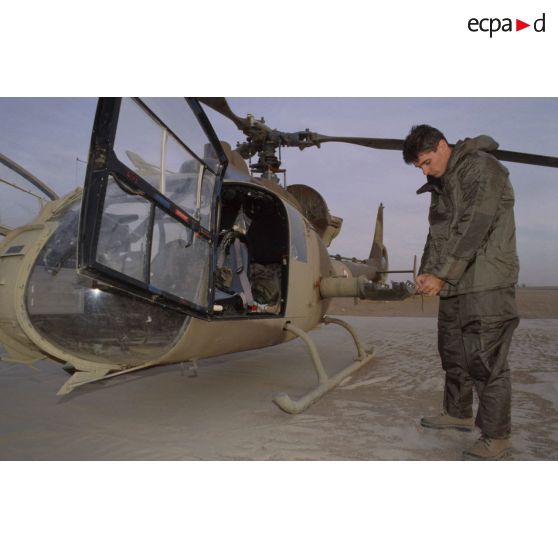 Un membre de l'équipage d'un d'hélicoptère de combat Gazelle Hot du 5e RHC revêt la tenue S-3P (survêtement de protection à port permanent) lors d'un exercice NBC.