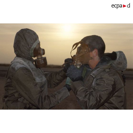 Un soldat en tenue S-3P (survêtement de protection à port permanent) et portant l'ANP (appareil normal de protection) ôte le masque de son camarade lors de l'exercice NBC du 1er RI.