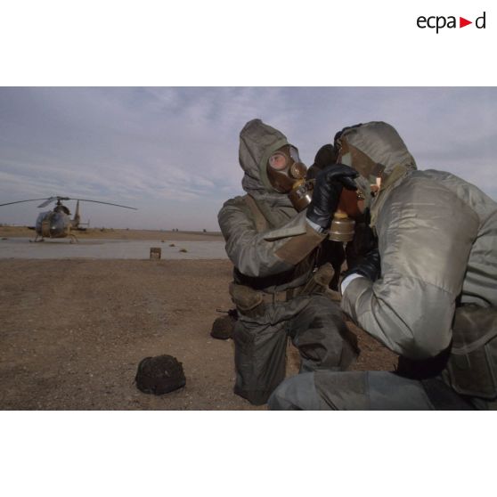 Un soldat en tenue S-3P (survêtement de protection à port permanent) et portant l'ANP (appareil normal de protection) ôte le masque de son camarade lors de l'exercice NBC du 1er RI.