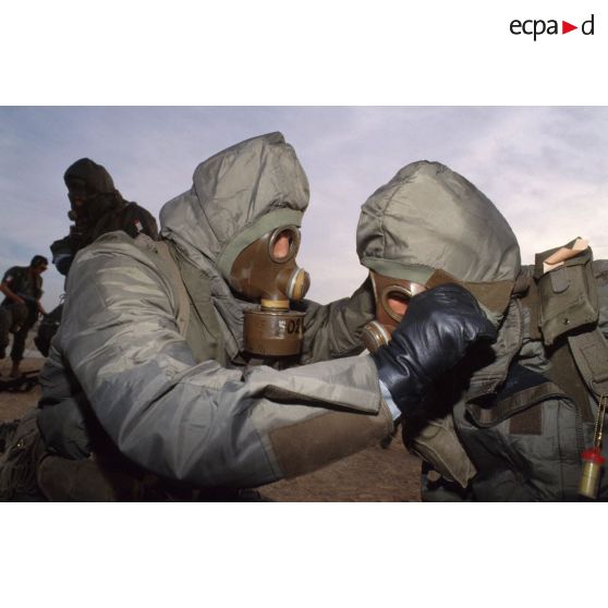 Un soldat en tenue S-3P (survêtement de protection à port permanent) et portant l'ANP (appareil normal de protection) ôte le masque de son camarade lors de l'exercice NBC du 1er RI.