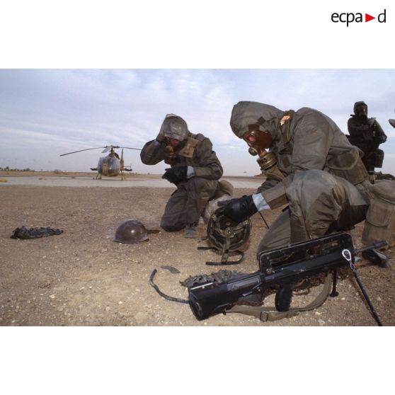 Deux soldats en tenue S-3P (survêtement de protection à port permanent) et portant l'ANP (appareil normal de protection) se décontaminent grâce au gant de décontamination chimique d'urgence lors de l'exercice NBC du 1er RI.
