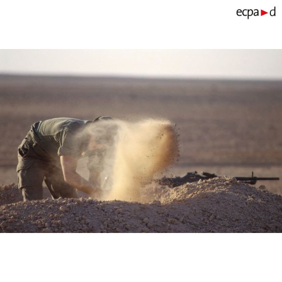 Installation du bivouac du 1er RI pour la nuit, un militaire creuse un trou de combat.