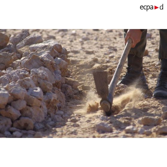 Installation du bivouac du 1er RI pour la nuit, un militaire creuse un trou de combat à la pioche.