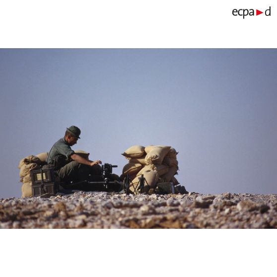 Poste de combat et d'observation au bivouac du 1er RI. Un soldat est posté derrière des sacs de sable avec une mitrailleuse Browning 12,7 mm.