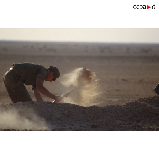 Installation du bivouac du 1er RI pour la nuit, un militaire creuse un trou de combat.