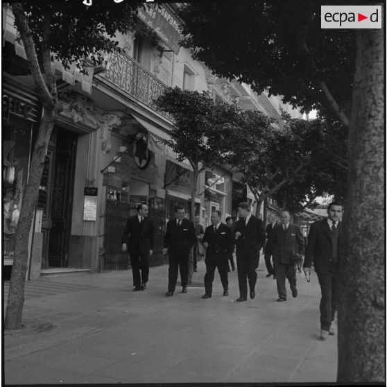Robert Lacoste, ministre de l'Algérie, avec sa délégation, sur un trottoir d'Alger.