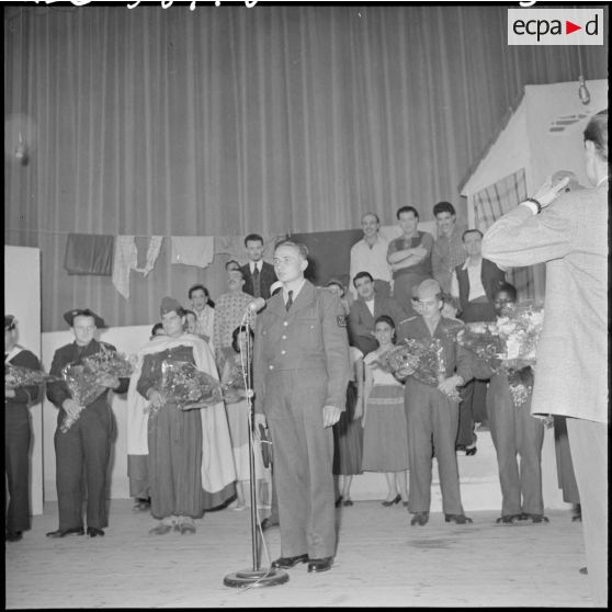 Un militaire parle au micro sur la scène du théâtre.