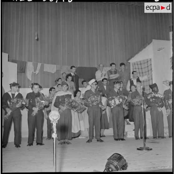 Les militaires de toutes armes reçoivent des bouquets de fleurs sur la scène du théâtre.