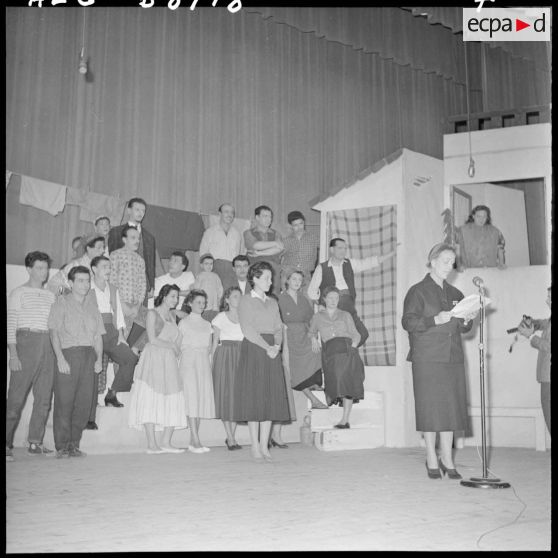 Une femme lit un texte sur la scène du théâtre.