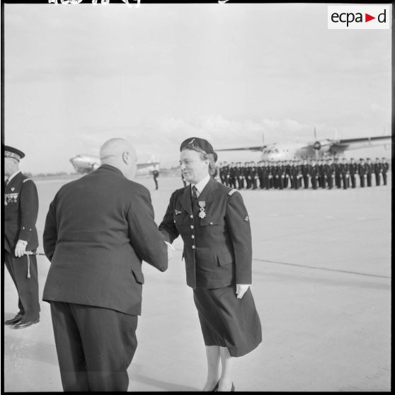 Louis Christiaens, secrétaire d’État aux forces armées de l'Air, remet  la croix de chevalier à une infirmière pilote de l’armée de l’Air (IPSA) à Maison-Blanche.