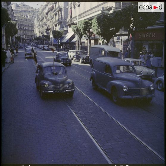 Un voiture avec un drapeau tricolore dans une rue d’Alger lors de la visite de Jacques Soustelle.