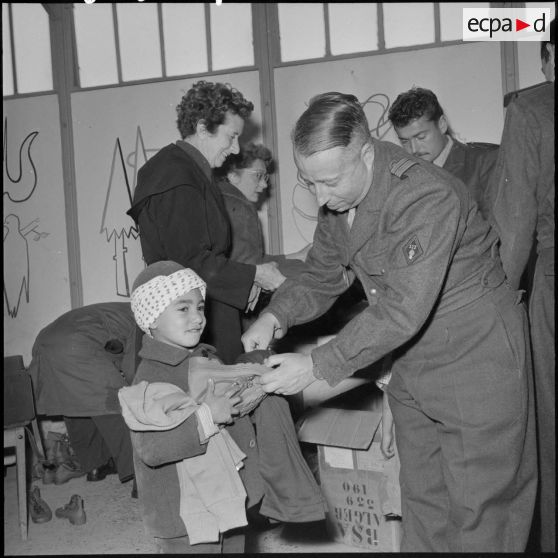 Le colonel Pechaudra distribue des vêtements à un élève.