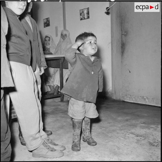 Un petit garçon fait le salut militaire.