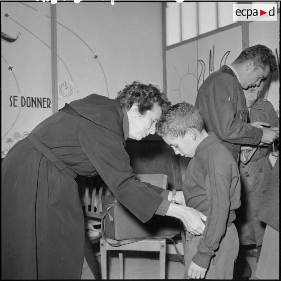 Madame Massu aide un élève à s’habiller.