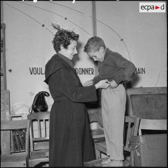 Madame Massu aide un élève à s’habiller.