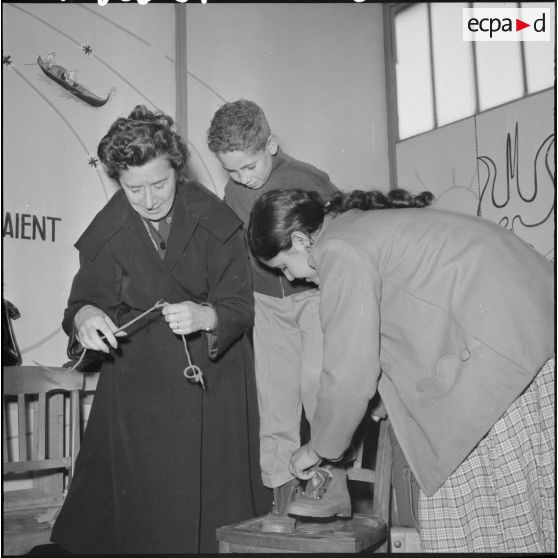 Madame Massu aide un élève à s’habiller.