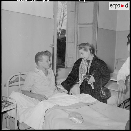 Madame Salan rend visite aux malades hospitalisés.