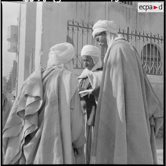 Trois habitants de Bou-Saâda consultent un tract.