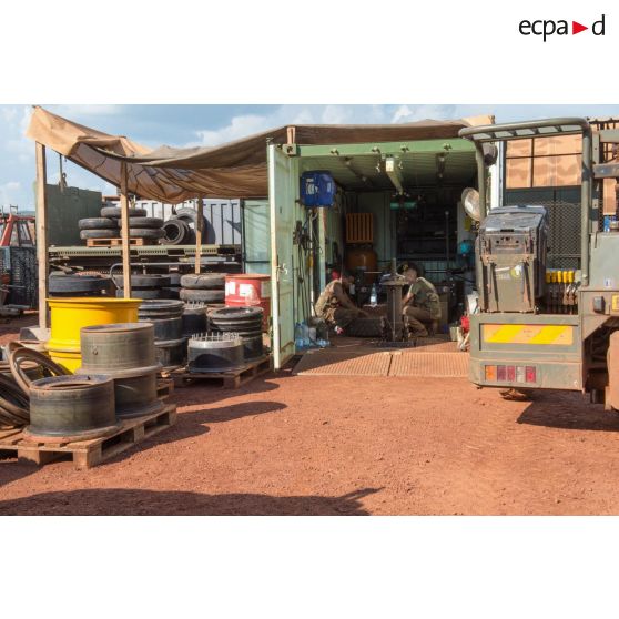 Des mécaniciens effectuent une réparation sur la roue d'un véhicule, à l'atelier de réparation mécanique du train de combat du camp de M'Poko de Bangui.