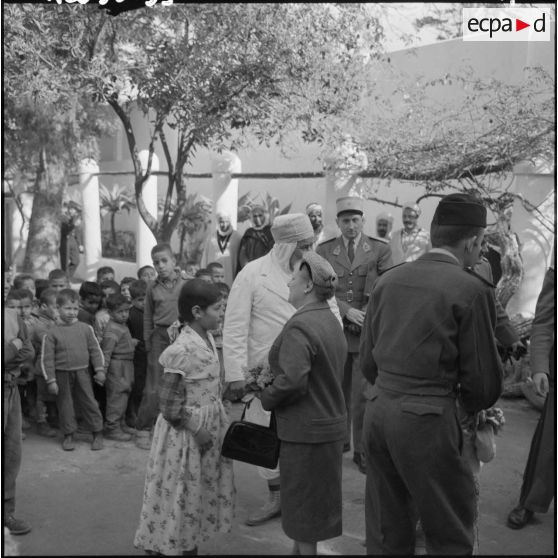 Madame Lacoste reçoit un bouquet de bienvenue lors de sa visite dans la cité Mahieddine d’Alger.