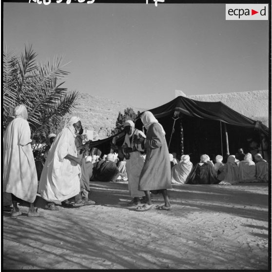 Un groupe d'ommes en tenue traditionnelle devant une tente.