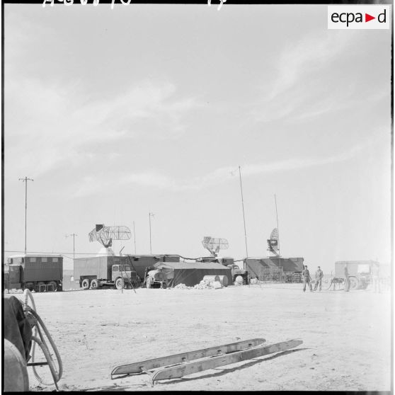 Antennes radar sur des camions dans un campement.