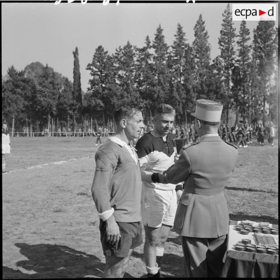 Un officier remet une coupe à un joueur de rugby lors d'une compétition.