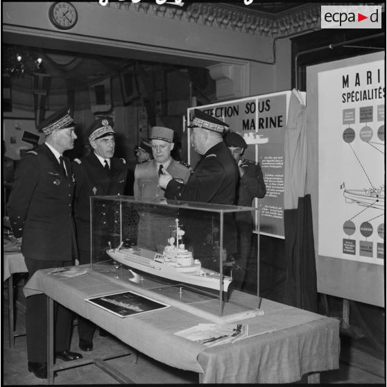 Le général d'armée Salan et des officiers de marine devant une maquette de bateau lors d'une exposition de la Marine à Alger.