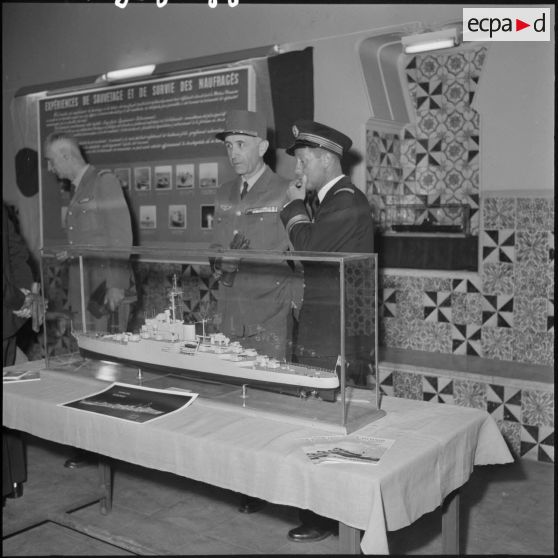 Officiers devant une maquette de bateau lors d'une exposition de la Marine à Alger.