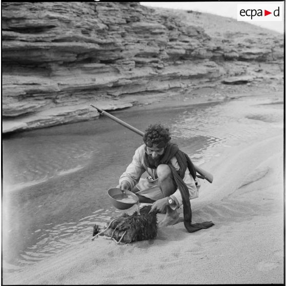 Un homme de la tribu Reguibat récupère de l'eau au bord d'une rivière.