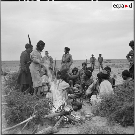 Un groupe de nomades Reguibat autour d'un feu dans le désert saharien.