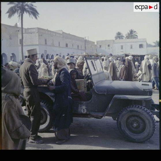 Légionnaires à bord d'un véhicule dans une ville.