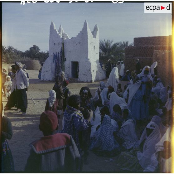 Villageois réunis autour d'un bâtiment carré.