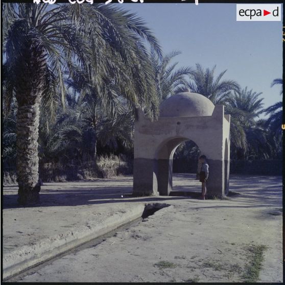 Un enfant contre une contruction en pierre au bord d'un canal.